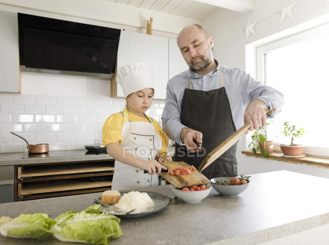 Daughter and father preparing food while standing together in kitchen at home — Stock Photo