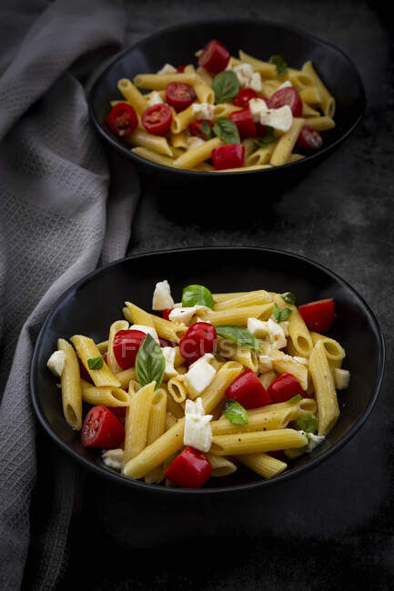 Pasta penne with mozzarella, tomatoes and basil — Stock Photo