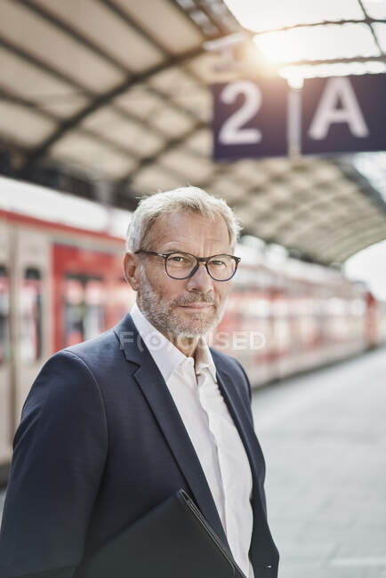 Businessman wearing eyeglasses standing on railroad station platform — Stock Photo