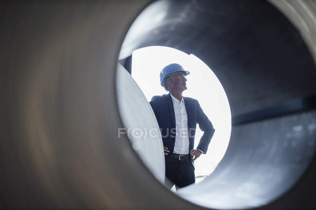 Nachdenklicher Geschäftsmann mit der Hand am Kinn, der an einer Blechrolle steht — Stockfoto