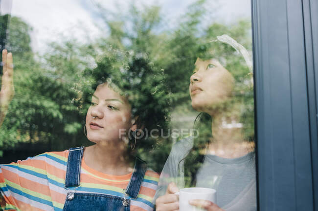 Amici che guardano attraverso la finestra della casa — Foto stock