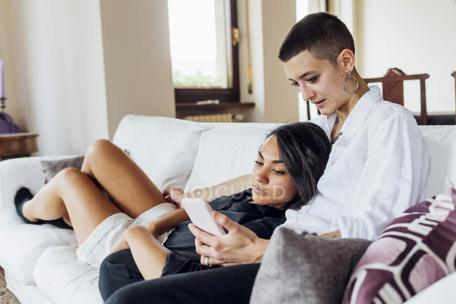 Queer mulher mostrando celular para namorada em casa — Fotografia de Stock