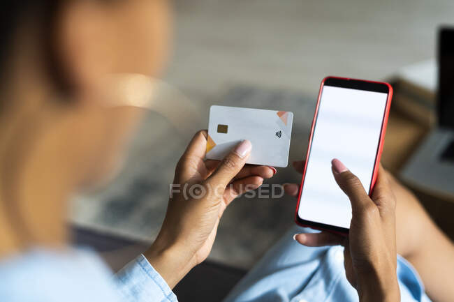 Jovem fazendo compras on-line através de telefone inteligente ao pagar com cartão de crédito — Fotografia de Stock