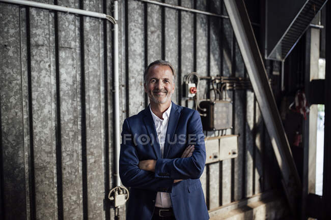 Profesional masculino con los brazos cruzados de pie en la industria del metal - foto de stock