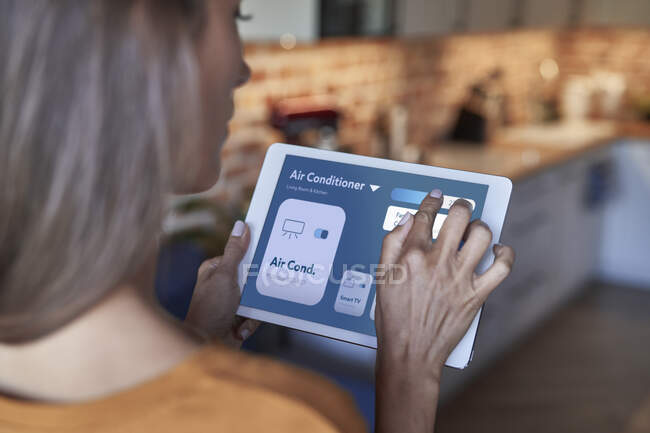 Mulher ajustando ar condicionado através de tablet digital em casa — Fotografia de Stock