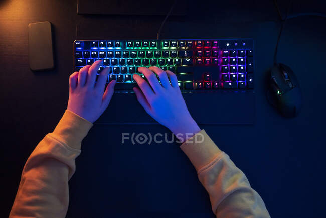 Garçon tapant sur clavier multicolore à la table — Photo de stock