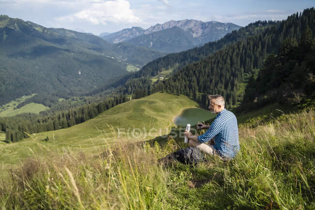 Hombre excursionista mirando a la montaña durante el día soleado - foto de stock