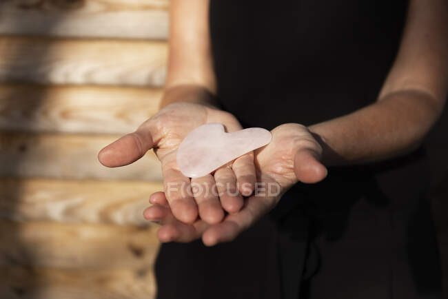 Masajista sosteniendo rosa gua sha herramienta - foto de stock