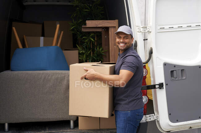 Чоловік, що тримає картонну коробку біля фургона. — стокове фото