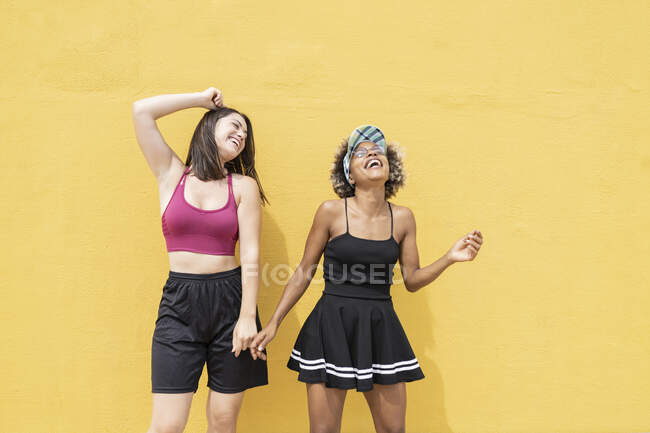 Веселі багатонаціональні друзі танцюють перед жовтою стіною. — стокове фото