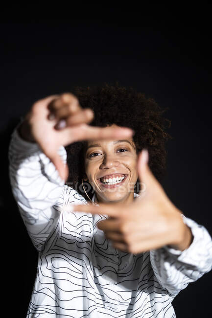Woman making finger frame against black background — Stock Photo