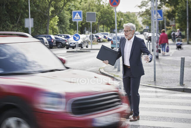 Shocked senior male professional crossing by speeding car — Stock Photo