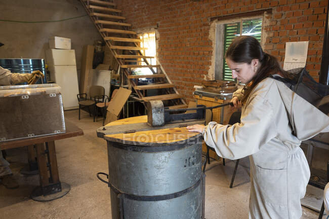 Female beekeeper working at shed — Stock Photo