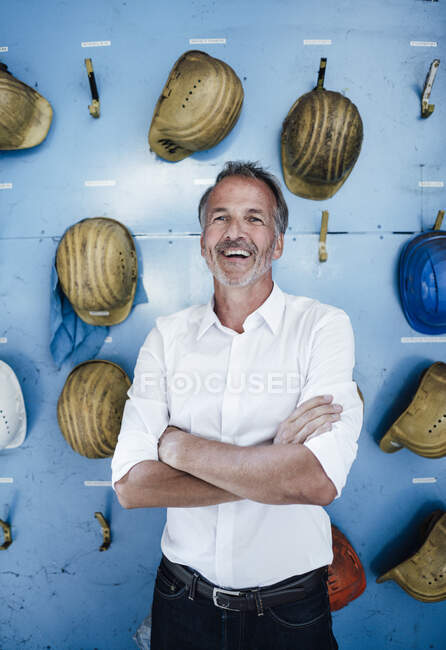 Allegro uomo d'affari professionale in piedi con le braccia incrociate davanti al muro — Foto stock