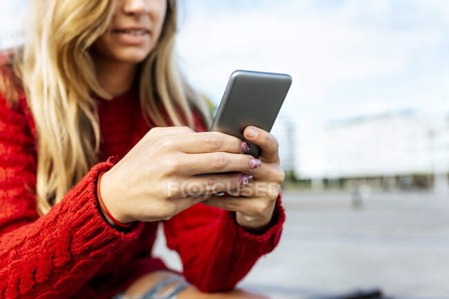 Femme utilisant un téléphone intelligent tout en étant assis sur le sentier — Photo de stock