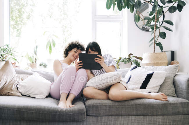 Junge Freundinnen nutzen digitales Tablet auf dem Sofa — Stockfoto