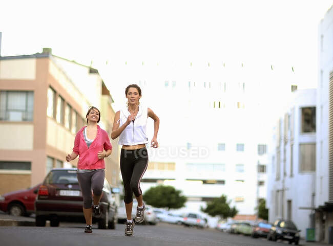 Mujeres jóvenes corriendo por la carretera - foto de stock