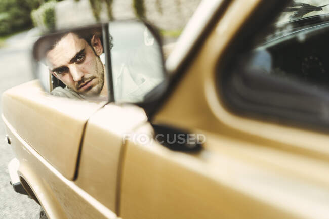 Spiegelbild eines ernstzunehmenden Mannes im Seitenspiegel des Autos — Stockfoto