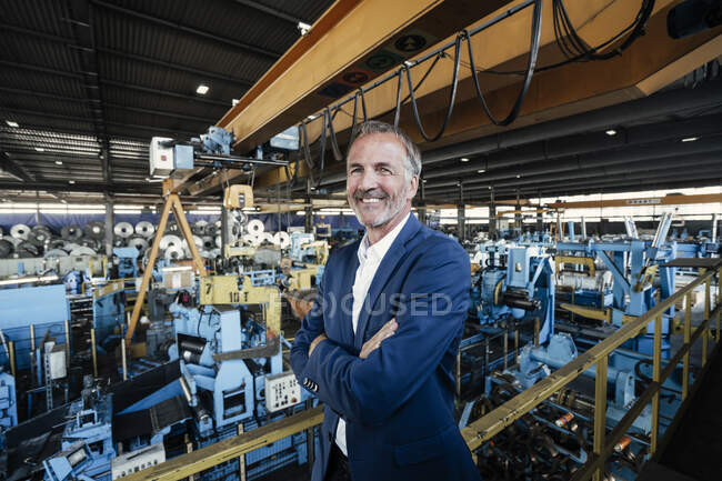 Senior businessman with arms crossed standing in industry — Stock Photo