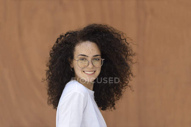 Mulher com cabelo encaracolado na frente da parede marrom — Fotografia de Stock