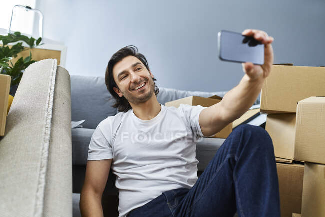 Uomo prendendo selfie attraverso smart phone mentre seduto a casa — Foto stock