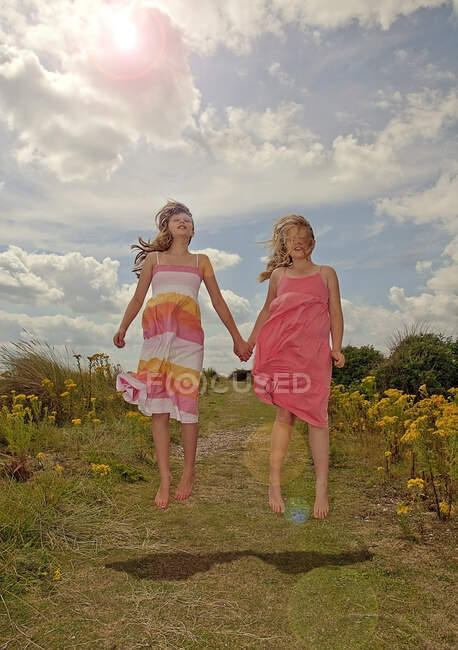 Carefree girls holding hands while jumping during sunny day — Stock Photo