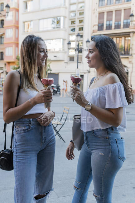 Молода дівчина дивиться один на одного тримаючи морозиво шишки в місті. — стокове фото