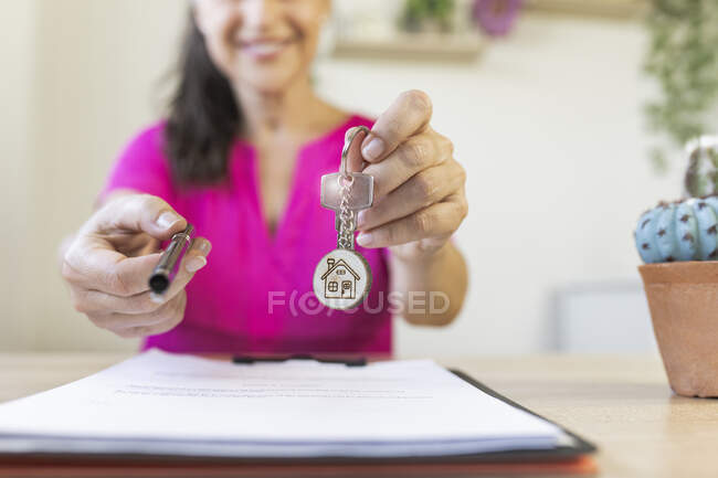 Female freelancer giving pen and house key during real estate agreement at home office — Stock Photo