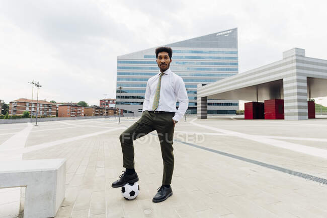 Jeune homme d'affaires debout avec ballon de football sur le sentier — Photo de stock