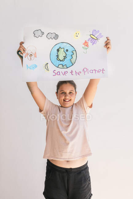 Усміхнена дівчинка тримає вдома плакат Землі. — стокове фото