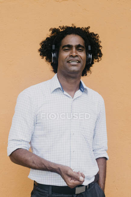 Afro-Mann mit Kopfhörern steht vor beiger Wand — Stockfoto