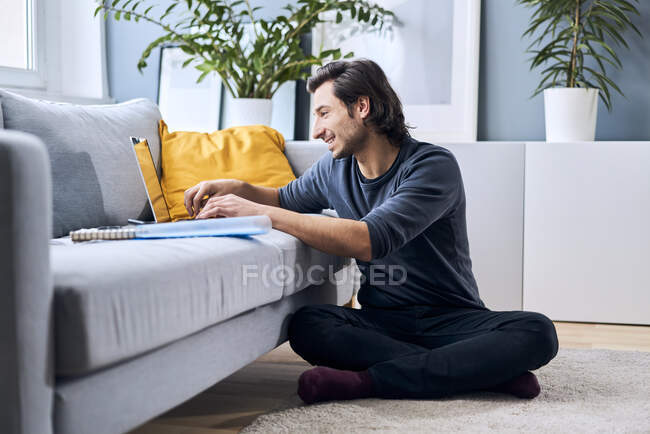 Male student learning while using laptop at home — Stock Photo