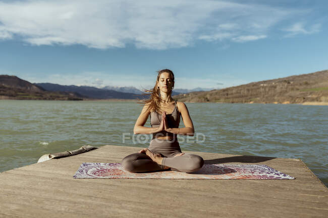 Jeune femme avec les mains serrées méditant le jour ensoleillé — Photo de stock