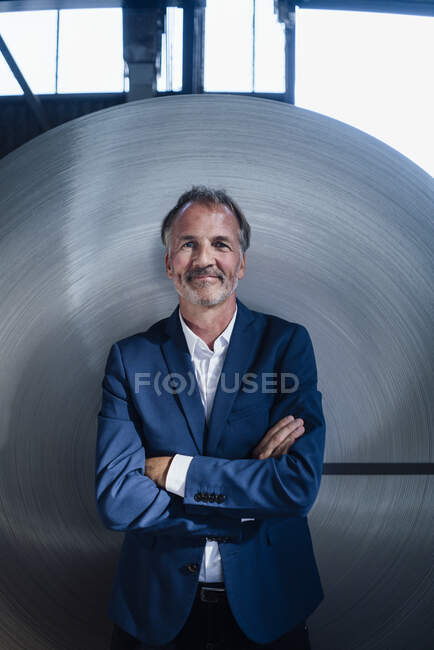 Male business professional standing with arms crossed in industry — Stock Photo