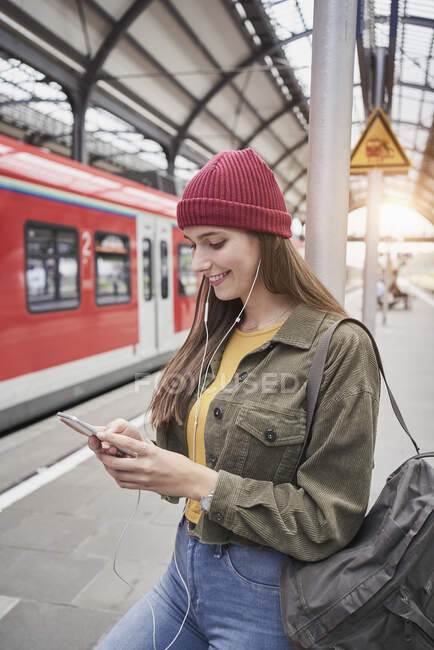 Mulher sorridente usando telefone celular enquanto está de pé na plataforma ferroviária — Fotografia de Stock