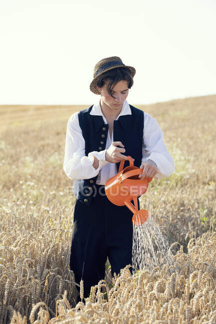Ragazzo adolescente con cappello campo irrigazione durante la giornata di sole — Foto stock