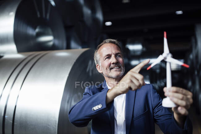 Male business professional holding wind turbine toy at warehouse — Stock Photo