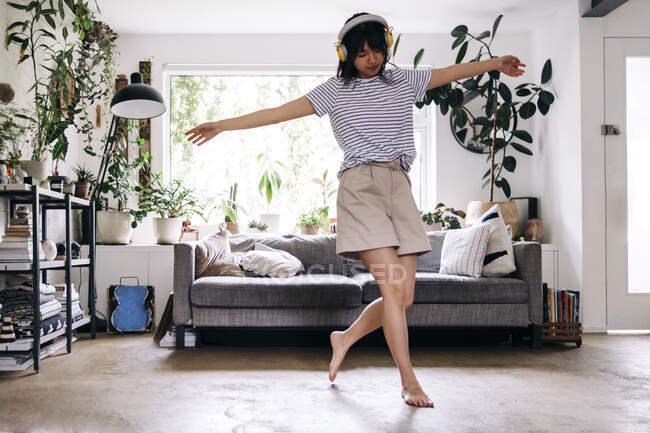 Unbekümmerte Frau mit ausgebreiteten Armen tanzt zu Hause — Stockfoto