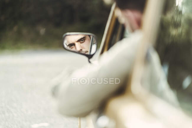 Reflexão do jovem no espelho lateral do carro — Fotografia de Stock