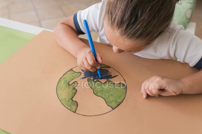 Девушка раскрашивает набросок планеты Земля дома — стоковое фото