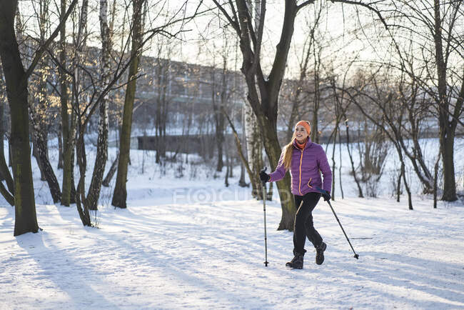 Женщина с походным столбом ходит по снегу зимой — стоковое фото
