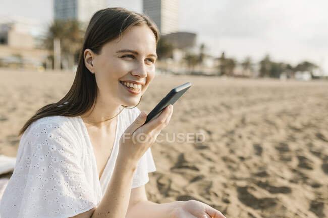Smiling woman talking on smart phone at beach — Stock Photo