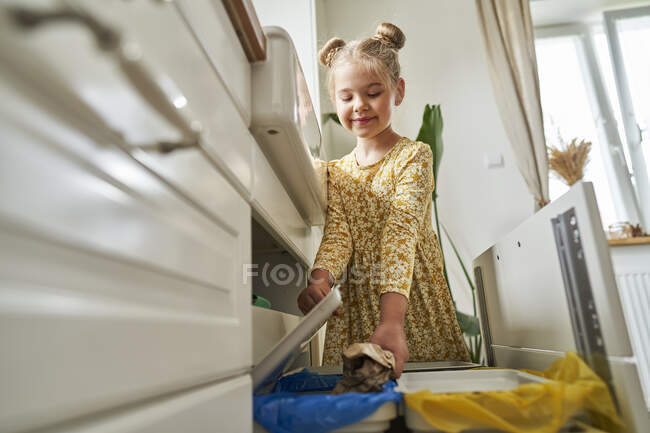Усміхнена дівчина викидає сміття вдома. — стокове фото