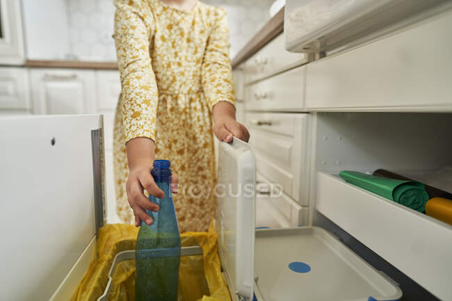 Mädchen wirft Plastikflasche zu Hause in Mülleimer — Stockfoto