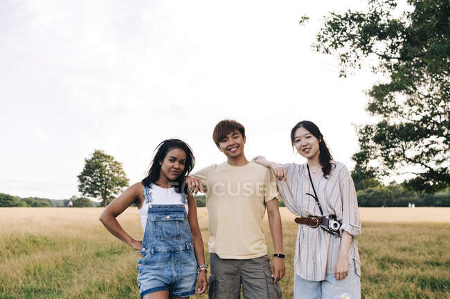 Smiling friends standing together at park — Stock Photo