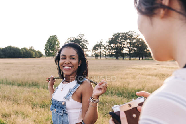 Lächelnde Frau hält Stock, während sie Freund mit Kamera ansieht — Stockfoto
