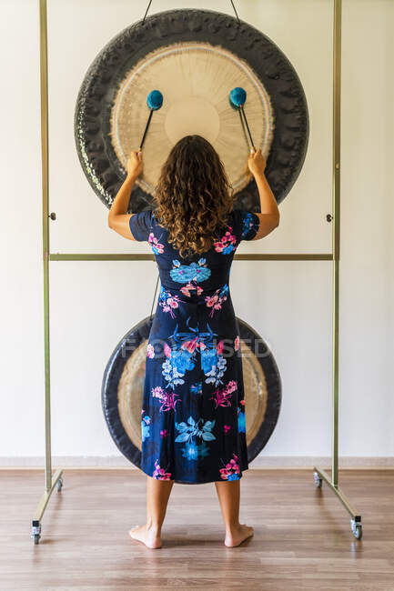 Femmina fonoterapista giocare a gong mentre in piedi in studio — Foto stock