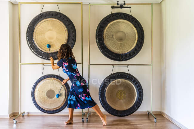 Terapista del suono femminile che gioca a gong con magli in studio — Foto stock
