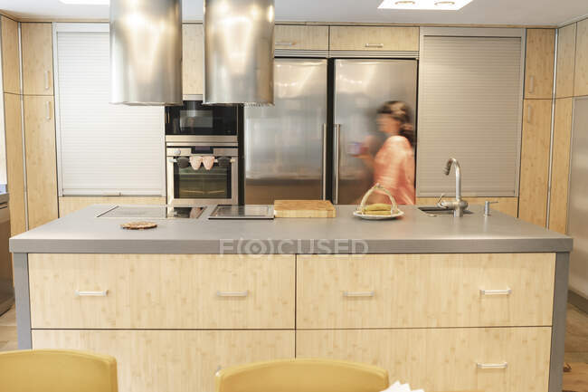 Woman walking by kitchen island and refrigerator in kitchen at home — Stock Photo