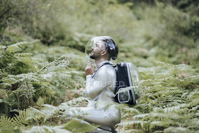 Ambientalista masculino com traje protetor agachando na floresta — Fotografia de Stock